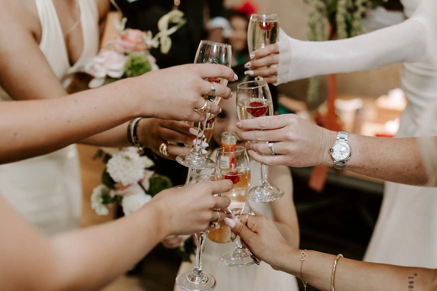 People holding wine glasses together in a celebratory toast at an elegant event.