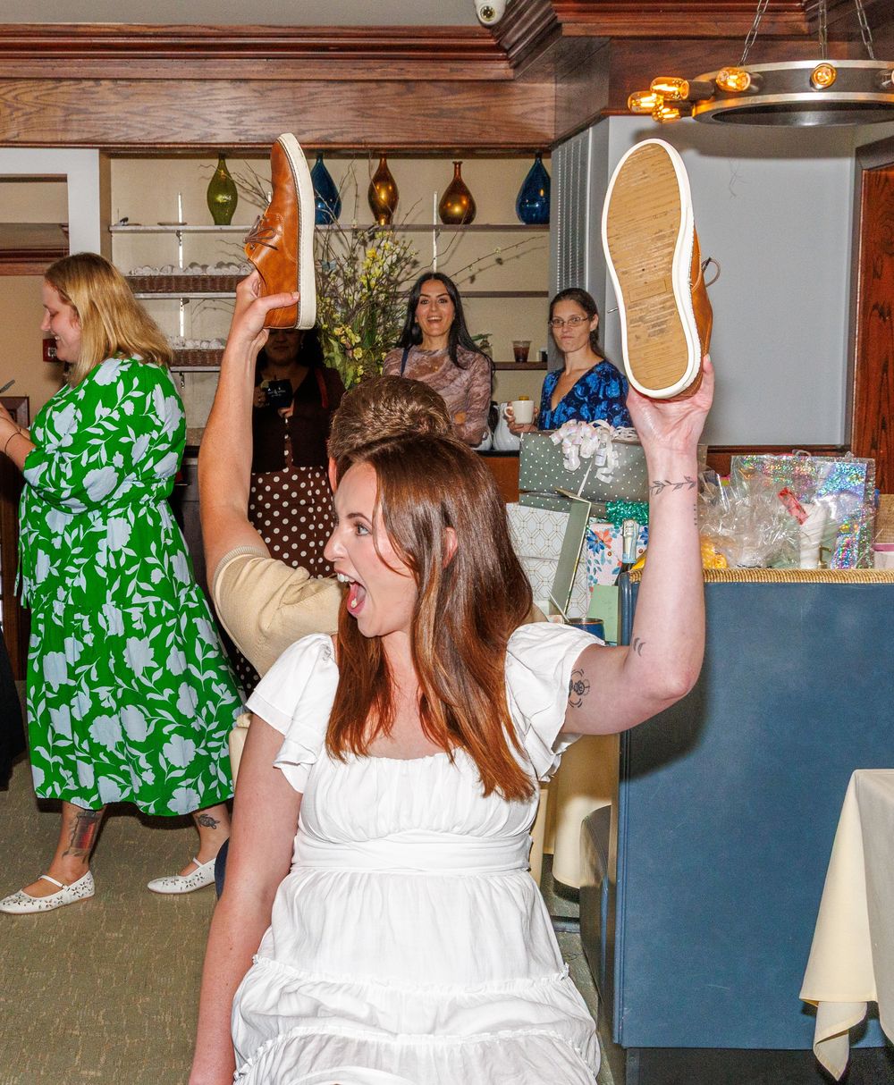 Party scene with people dancing and celebrating in a wood-paneled room with decorative lighting.
