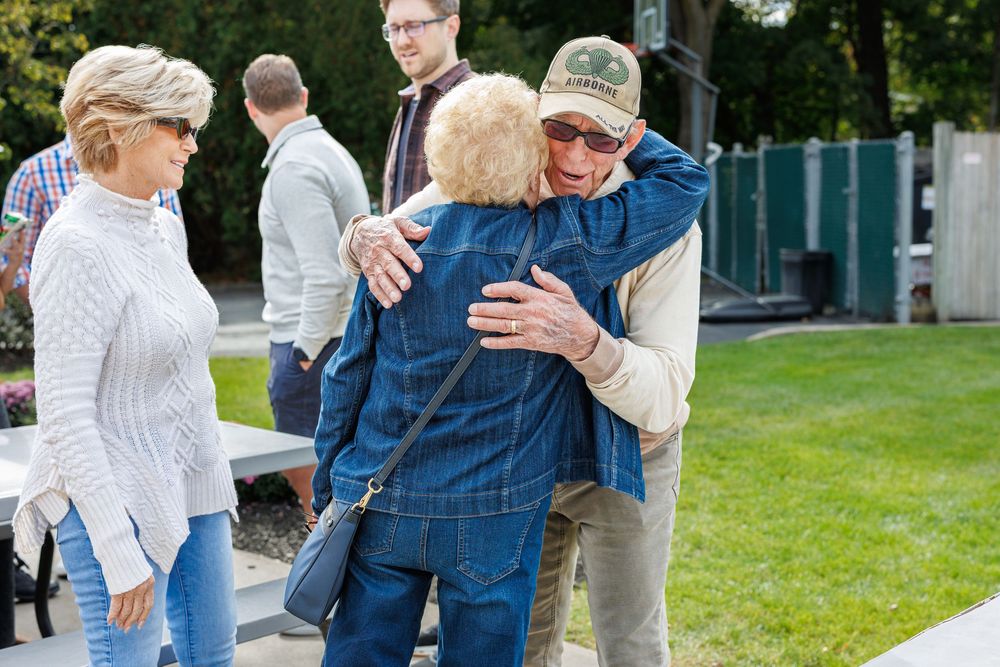Group of people gathered outdoors on a grassy lawn during a social event.