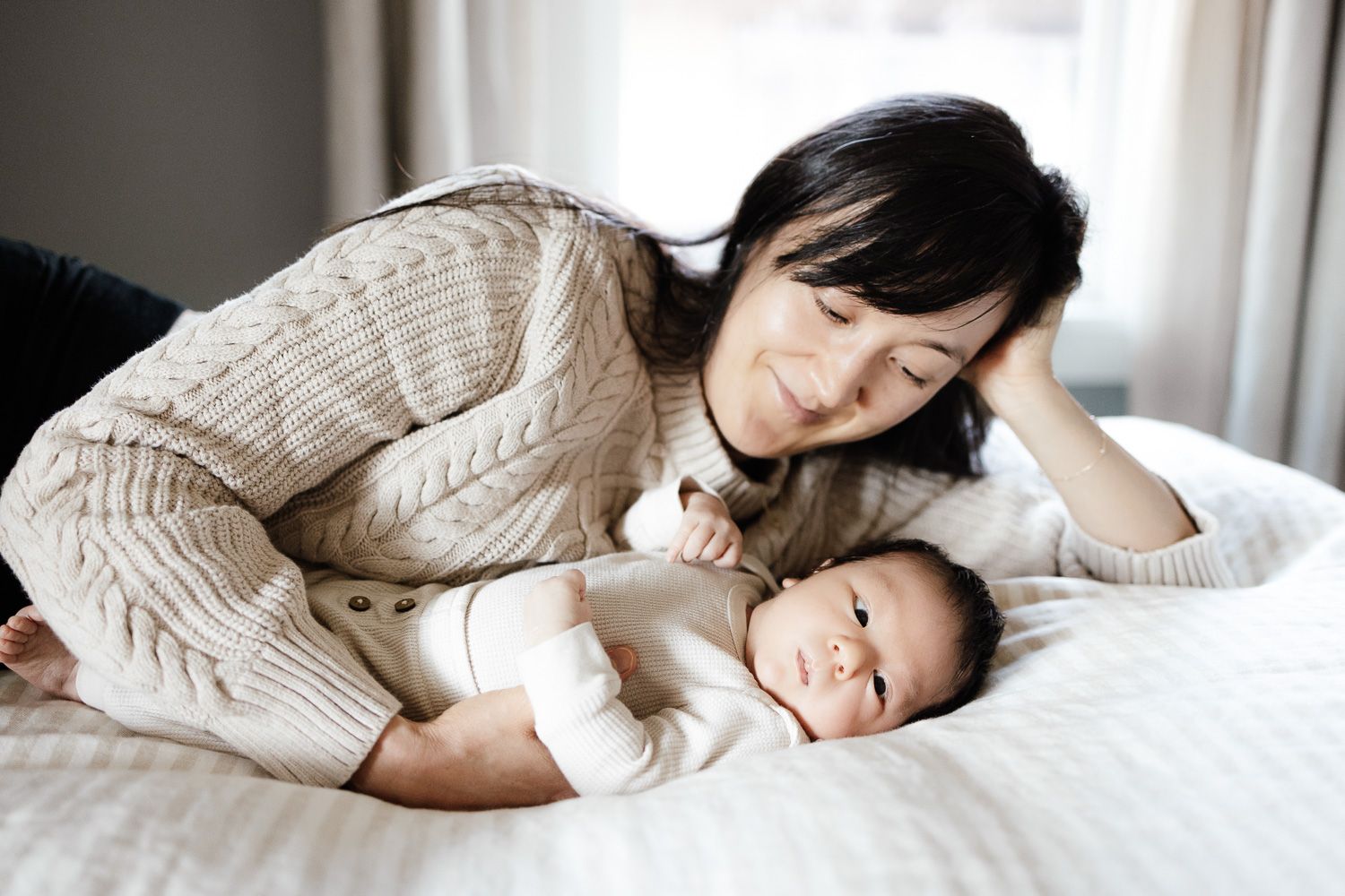 A mom lays next to her baby at their in-home baby photoshoot in the Bay Area