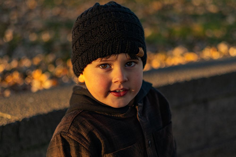 Candid portrait captured at sunset showing warm golden lighting on subject wearing winter hat.