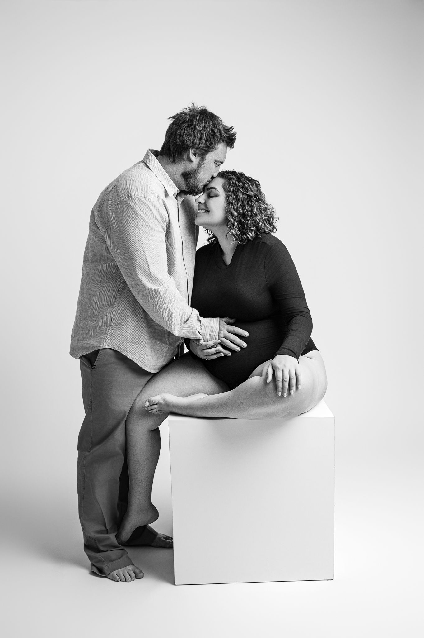 Black and white artistic photo series showing intimate poses between two people on a minimalist white background.