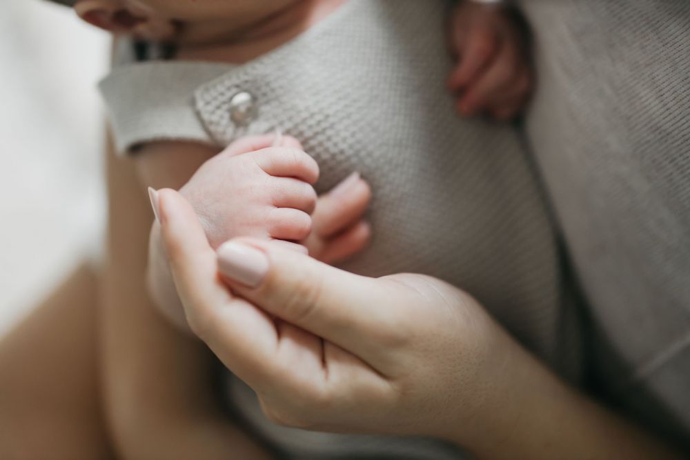 Close-up of hands holding a delicate silver ring against a soft white background.