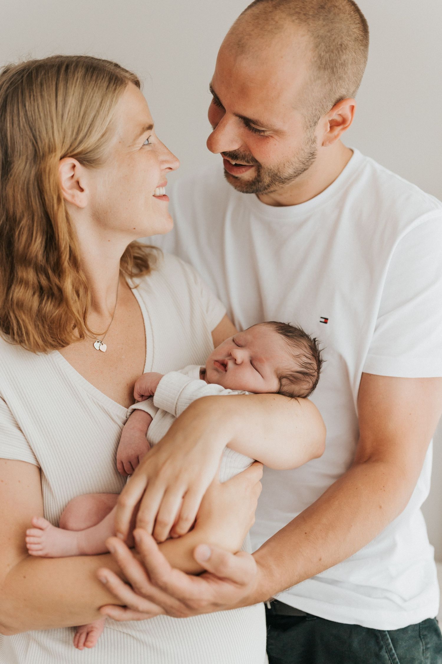 A tender family moment captured in a series of intimate photos against a light neutral background.