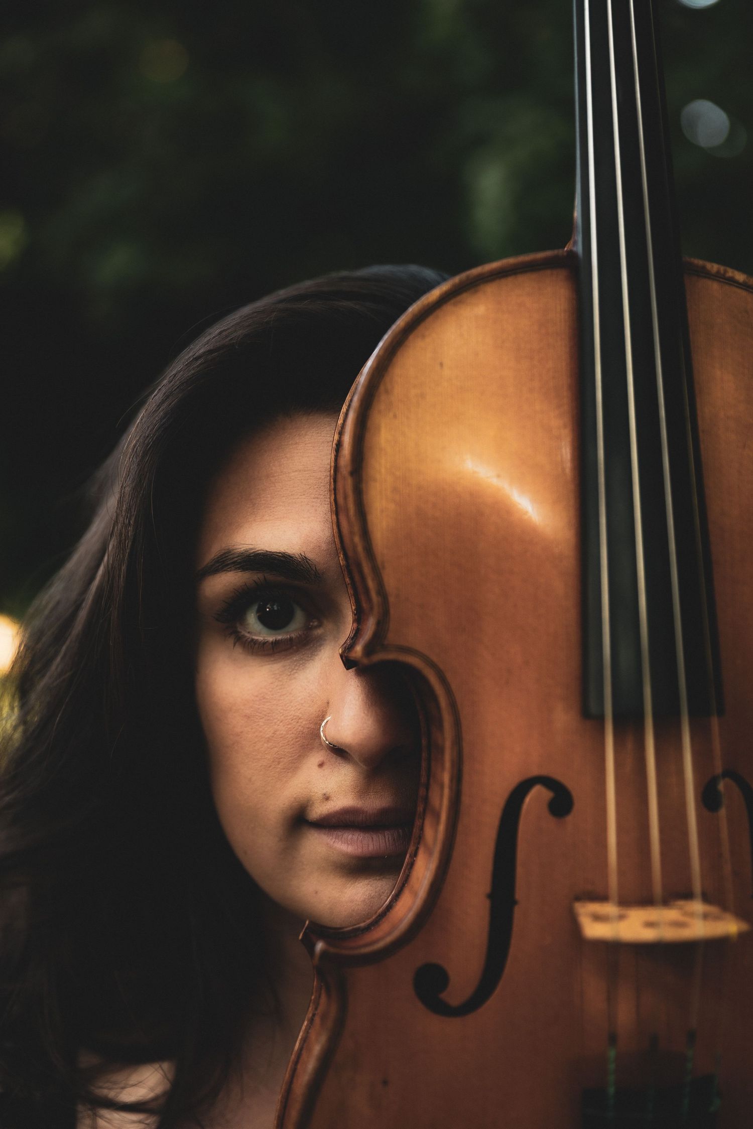 headshot of a woman, her face half hidden by her violin.