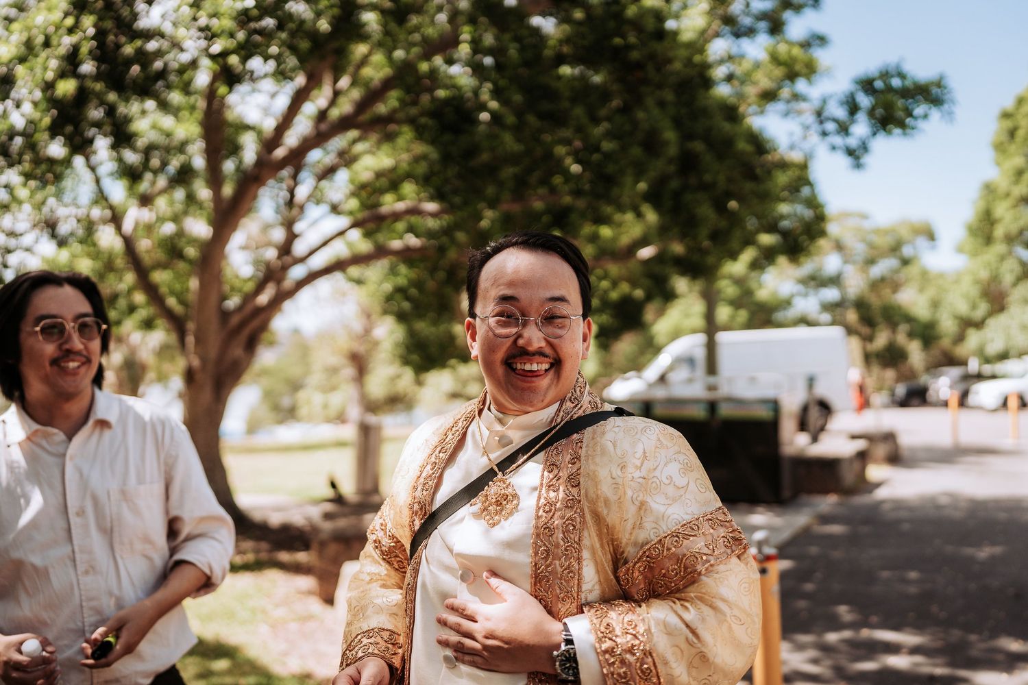 Wedding guests share laughter and joyful moments during an outdoor celebration on a sunny day.