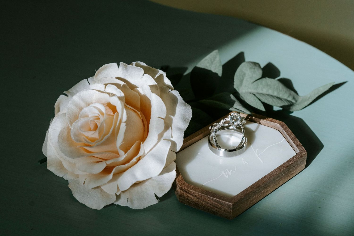 Delicate peach roses and vintage jewelry box arranged on soft blue fabric in romantic still life composition.