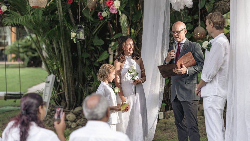 Wedding ceremony moments captured in a garden setting with white drapes and floral decorations.