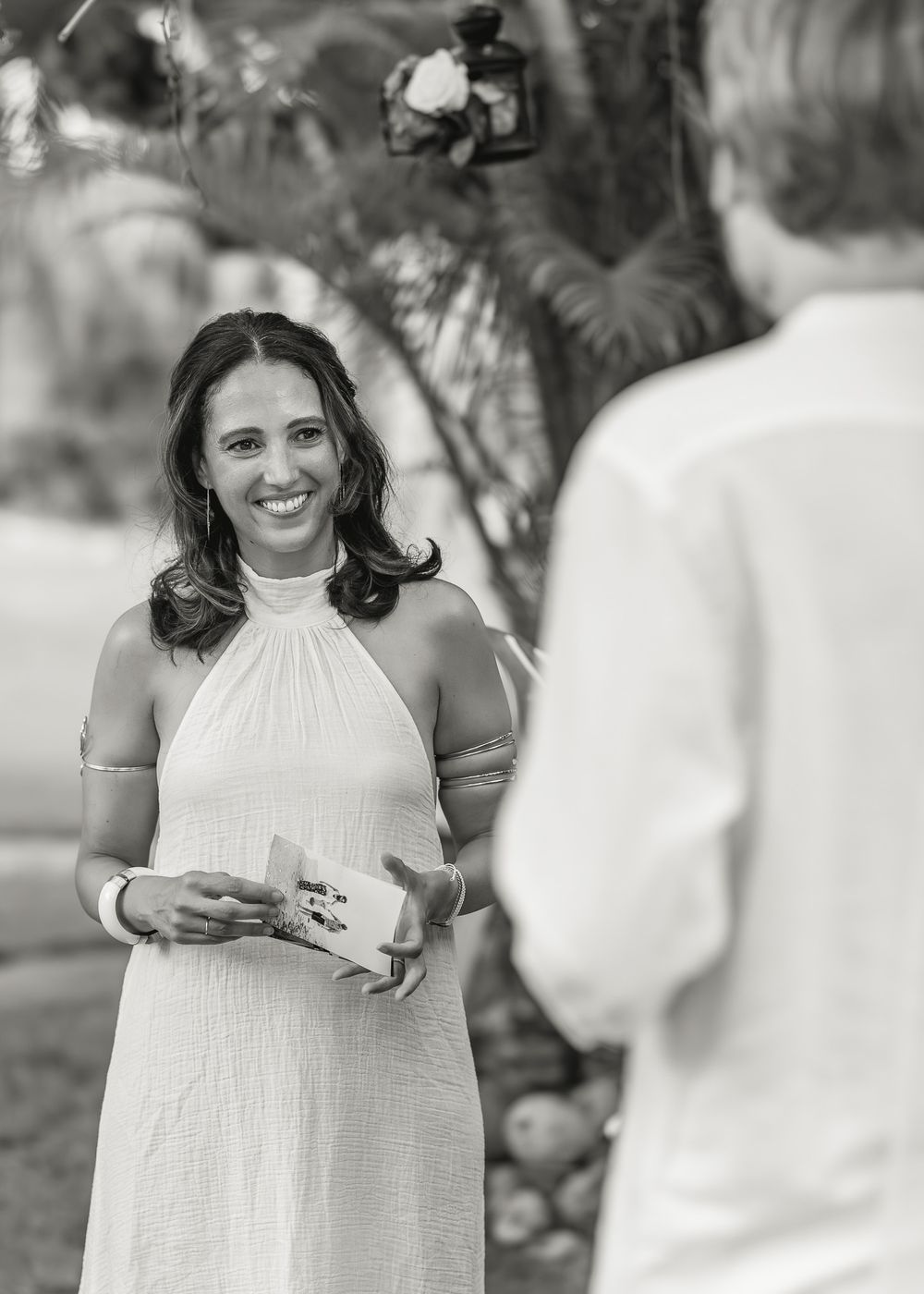 People dressed in white gather at an outdoor event with drinks and conversation.