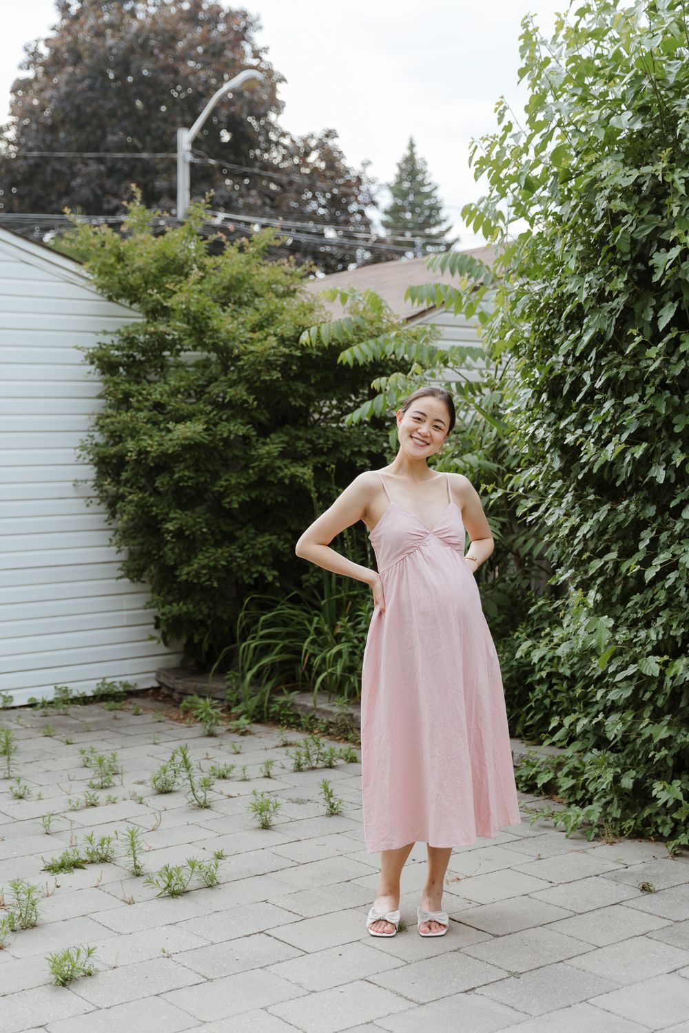Multiple shots of a pink dress being modeled in a backyard garden setting with stone pavers.