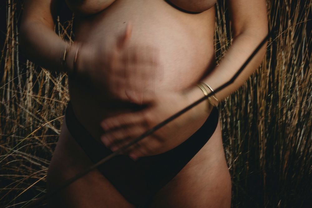 foto colorida detalhe mãos sobre a barriga grávida , mão em movimento em sessão gravida em Portugal