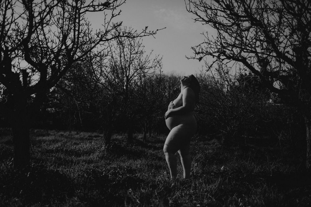 foto preto e branco grávida Nua na natureza com mãos na barriga durante sessão fotográfica de grávida em Caldas Da Rainha