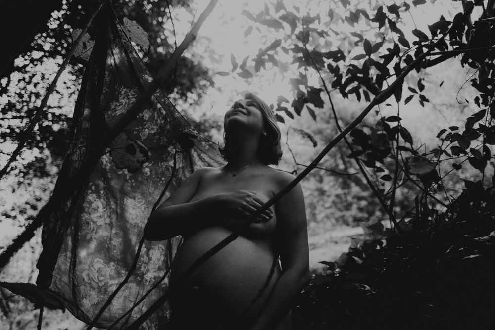 foto preto e branco grávida Nua na natureza com mãos na barriga durante sessão fotográfica de grávida em Caldas Da Rainha