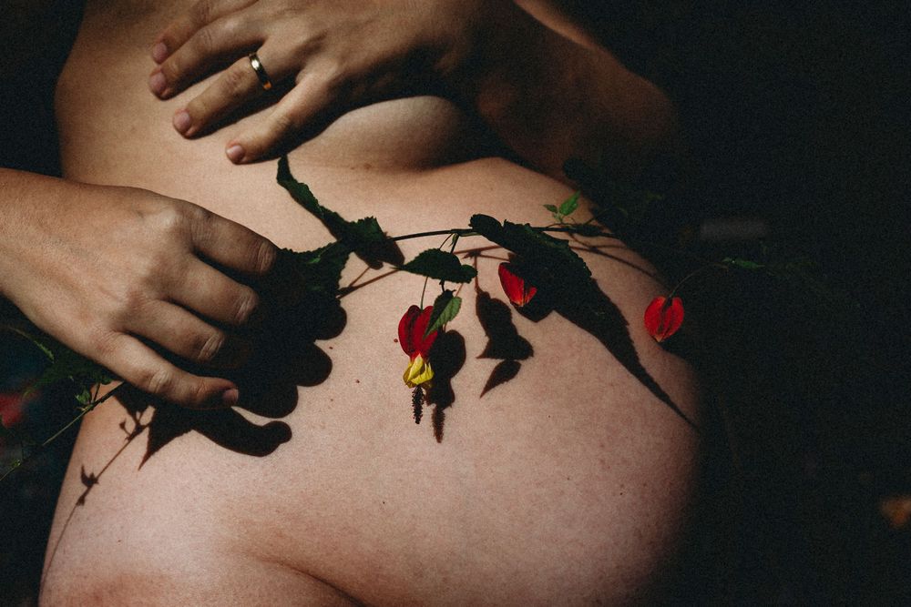 detalhe da barriga grávida com ramo de flor em foto colorida durante sessão de grávida em Caldas Da Rainha Portugal