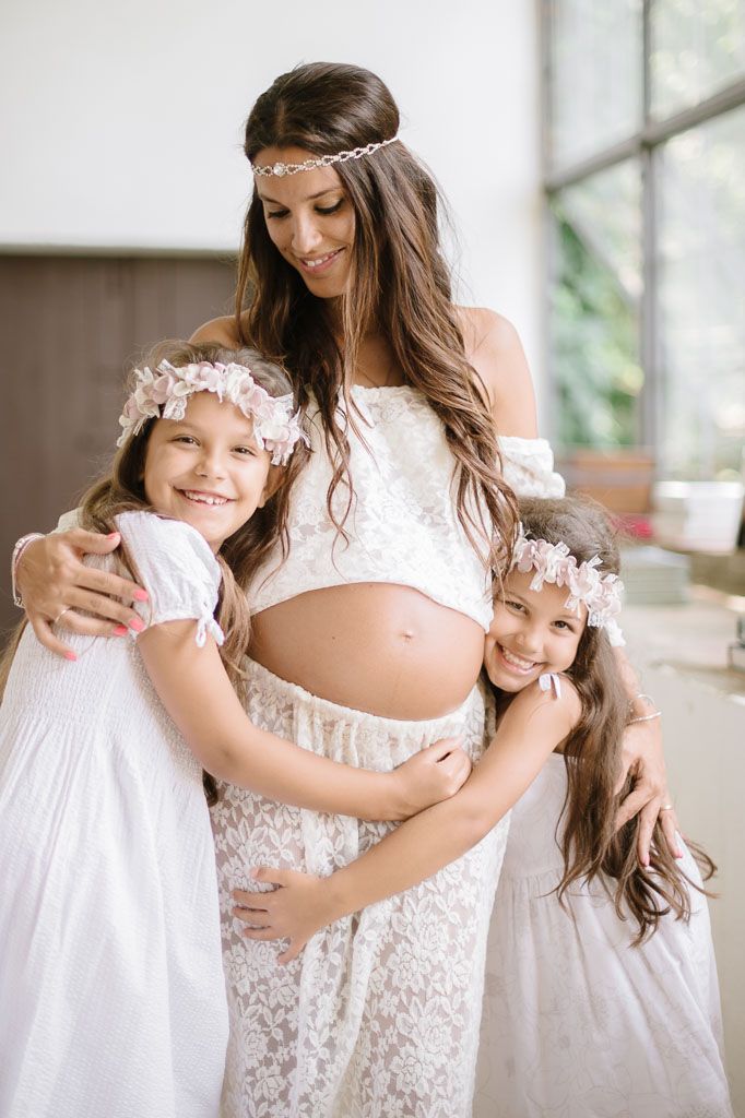 Sweet family maternity photo with children in matching white dresses.