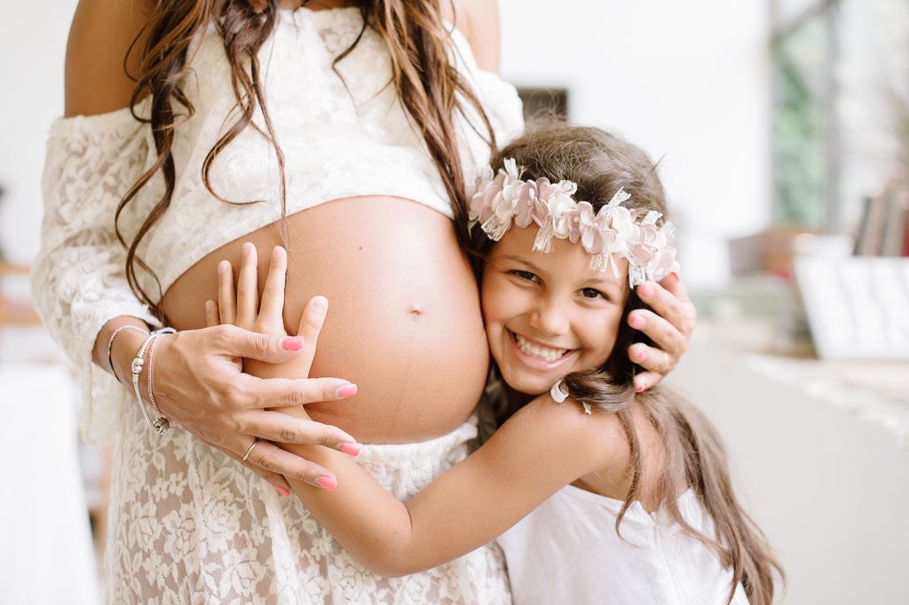 Joyful maternity moment with child embracing mother's pregnant belly.