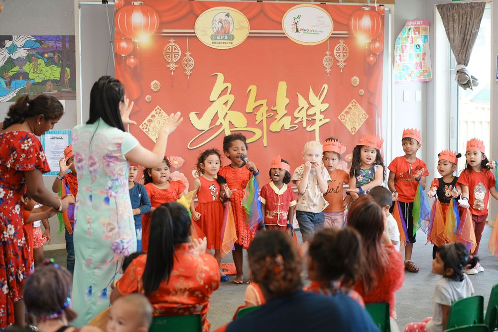 Event photography of a woman in Hanfu interacting with children at a kindergarten New Year party, by an Auckland event photographer.