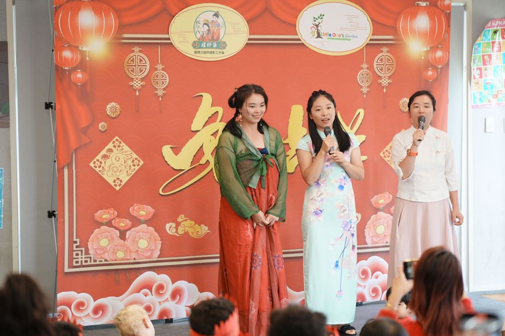 Event photography of a woman in Hanfu interacting with children at a kindergarten New Year party, by an Auckland event photographer.