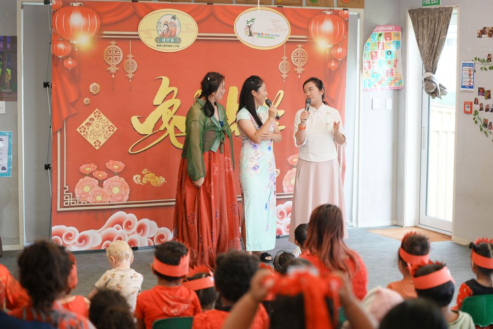 Event photography of a woman in Hanfu interacting with children at a kindergarten New Year party, by an Auckland event photographer.