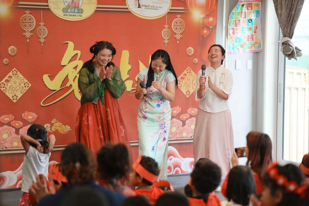 Event photography of a woman in Hanfu interacting with children at a kindergarten New Year party, by an Auckland event photographer.