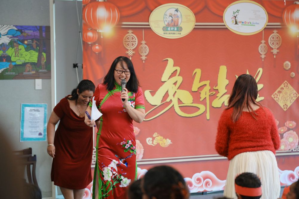 Event photography of a woman in Hanfu interacting with children at a kindergarten New Year party, by an Auckland event photographer.