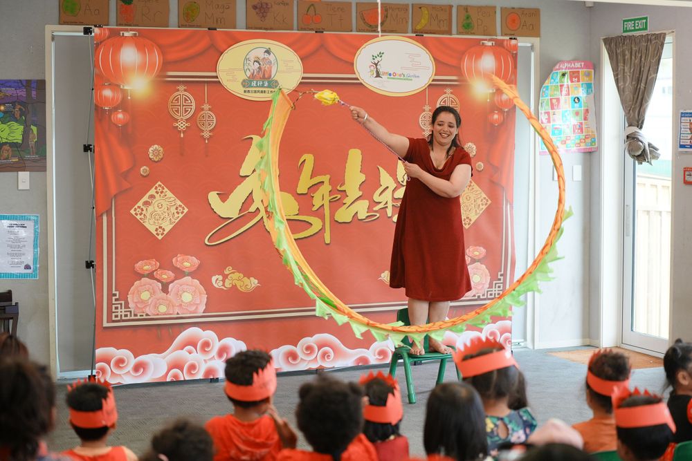 Event photography of a woman in Hanfu interacting with children at a kindergarten New Year party, by an Auckland event photographer.