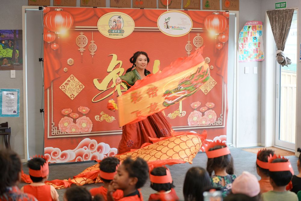 Event photography of a woman in Hanfu interacting with children at a kindergarten New Year party, by an Auckland event photographer.