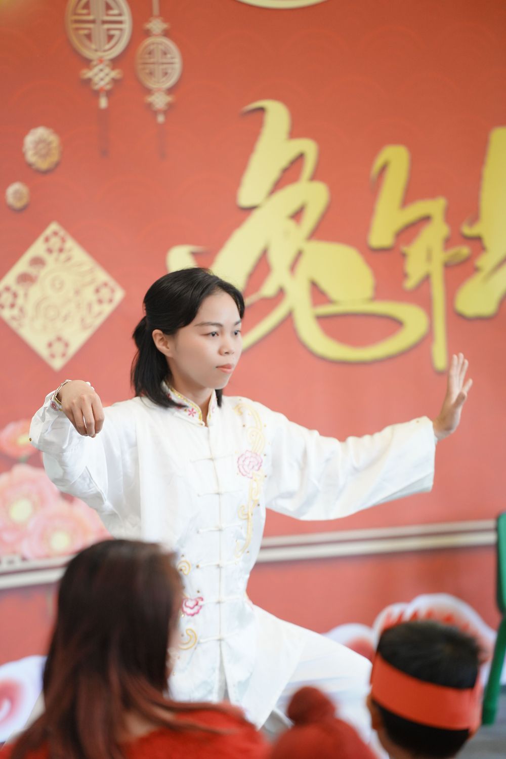 Event photography of a woman in Hanfu interacting with children at a kindergarten New Year party, by an Auckland event photographer.