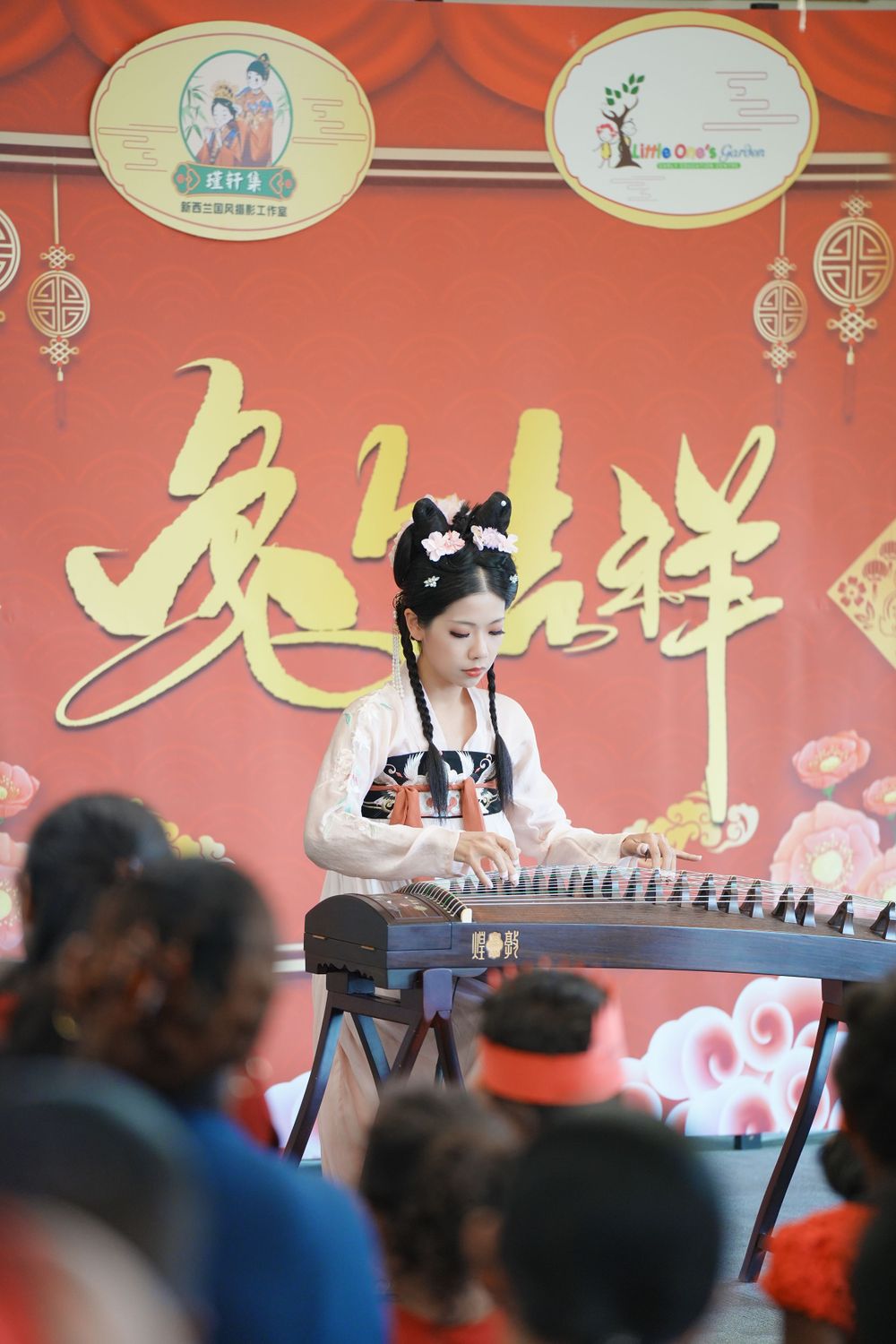 Event photography of a woman in Hanfu interacting with children at a kindergarten New Year party, by an Auckland event photographer.