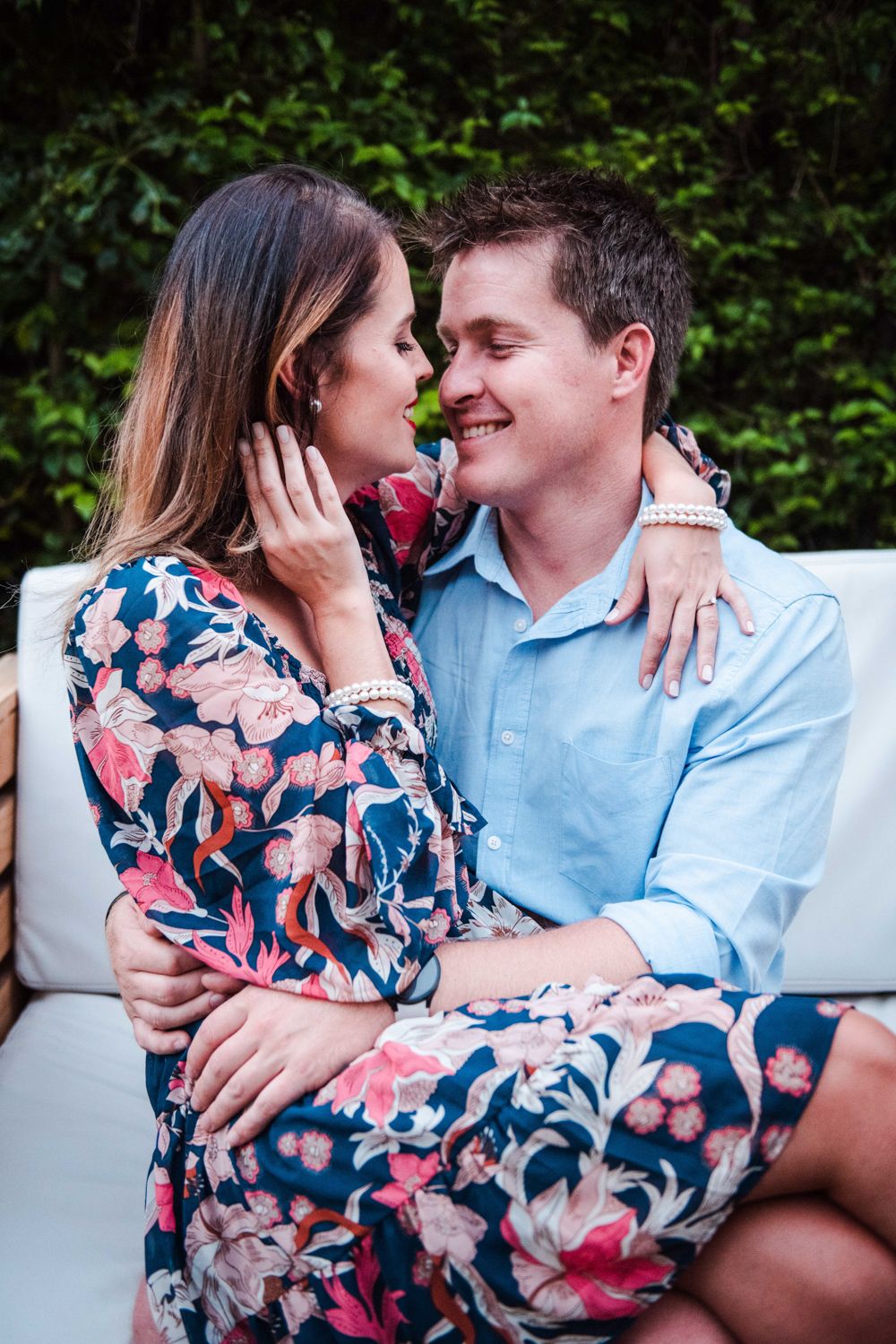 Couple posing affectionately in a sunlit garden path.