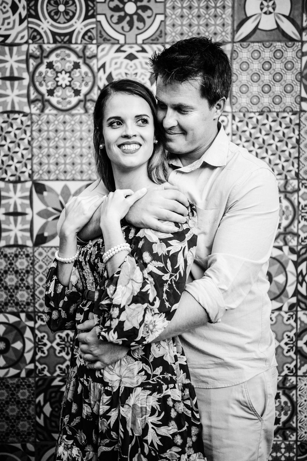 Happy couple smiling at each other, sitting casually on a stone wall.