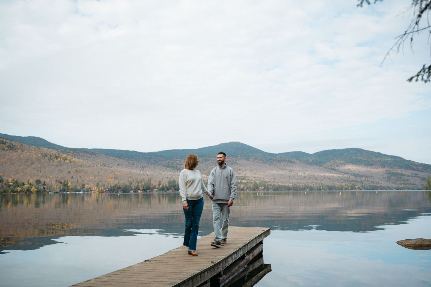 A scenic lake view with mountains in the background and a wooden dock extending into calm waters.