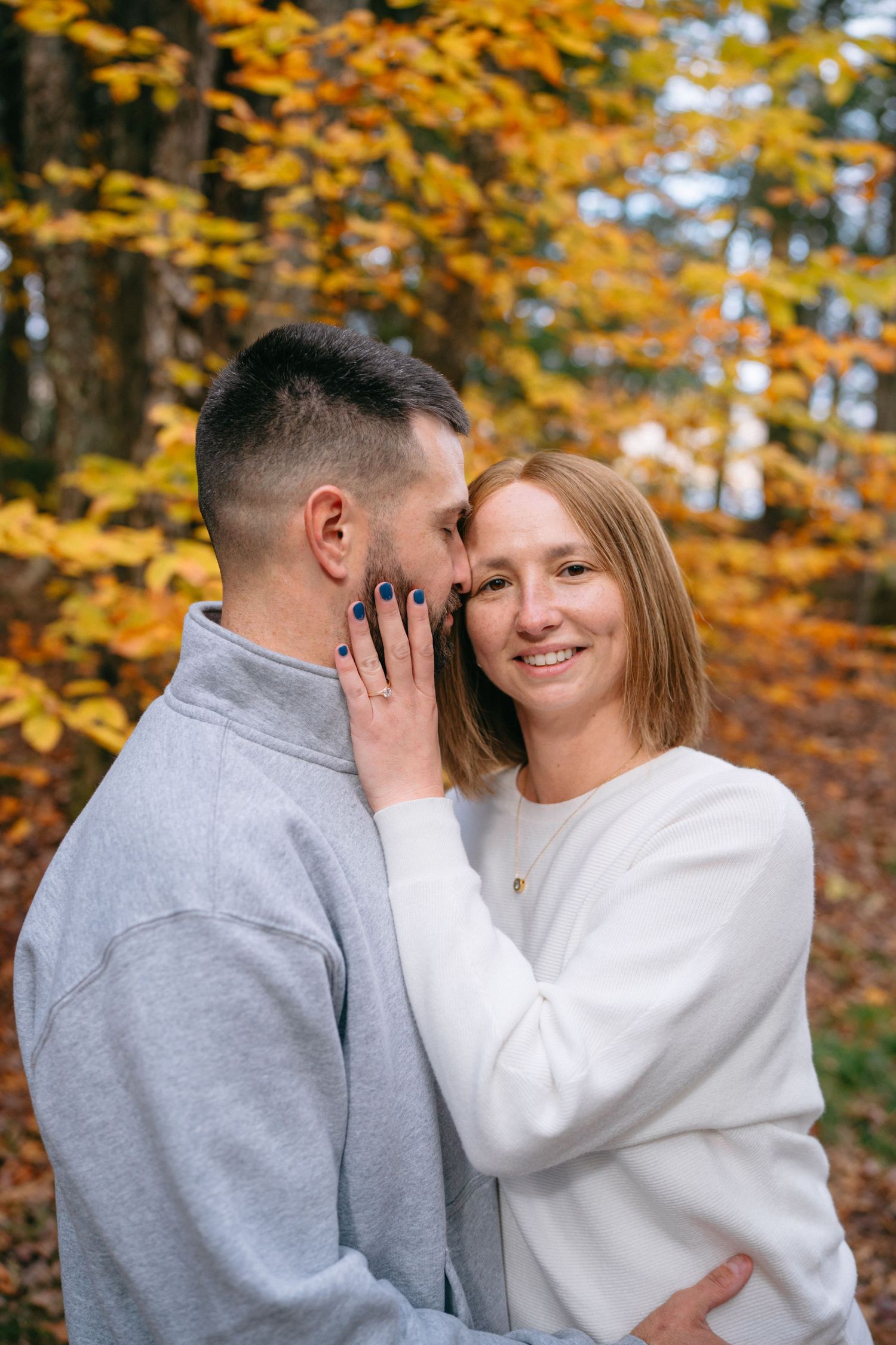 A romantic couple shares intimate moments against a backdrop of golden autumn foliage in a forest setting.