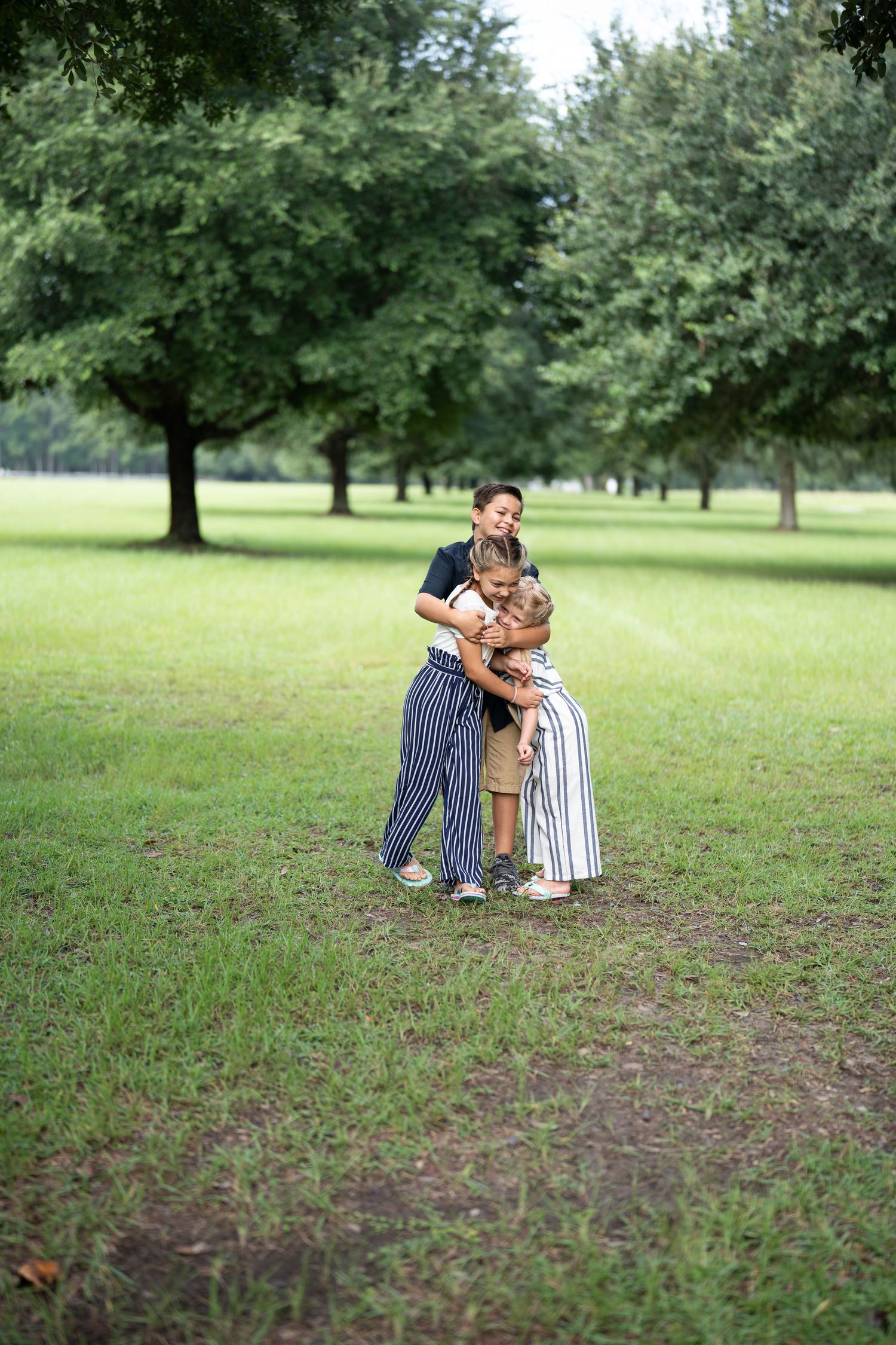 Two people in striped outfits embrace in green park setting.