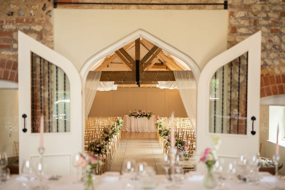 An elegant wedding venue interior with stone walls and arched windows decorated with white table settings.