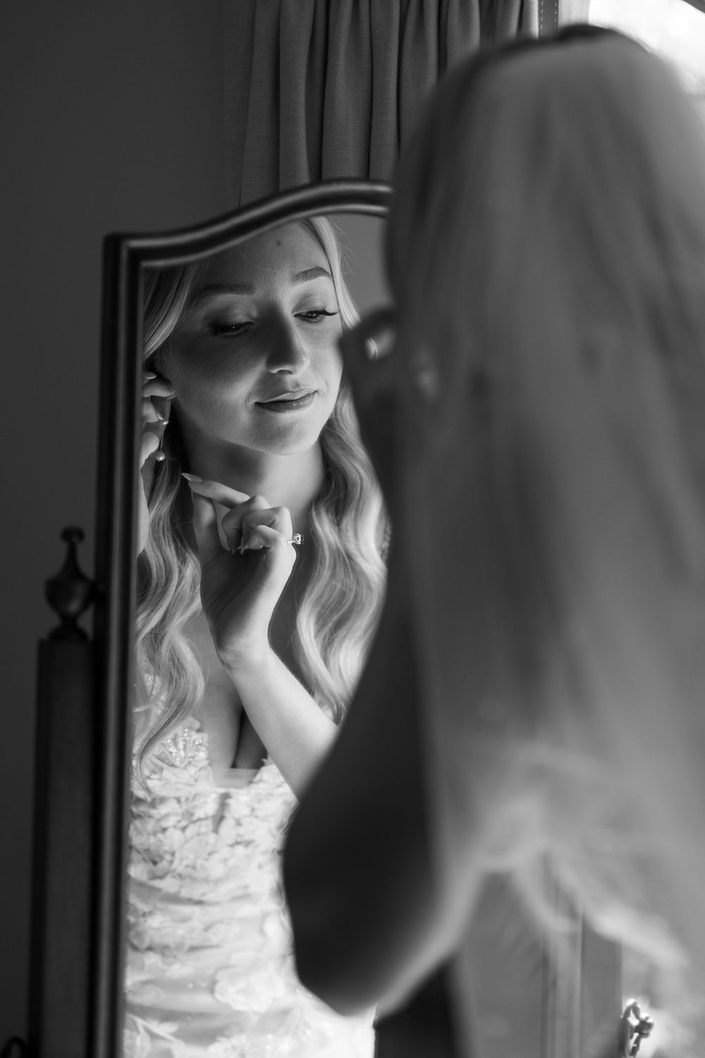 Black and white candid photos of a bride getting ready in her lace wedding dress.