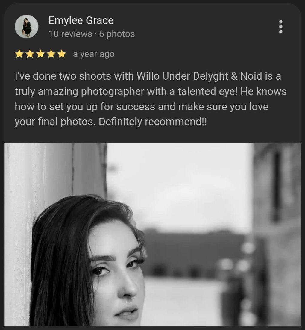 A professional headshot photograph of someone with dark hair and dramatic eye makeup against a neutral background.