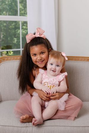 Two children sharing a sweet moment together on a gray couch with pink decor.