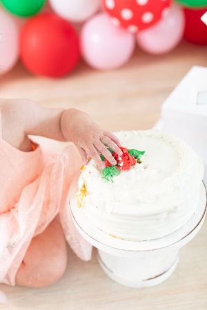 White frosted cake on pedestal with small decorative strawberries on top.