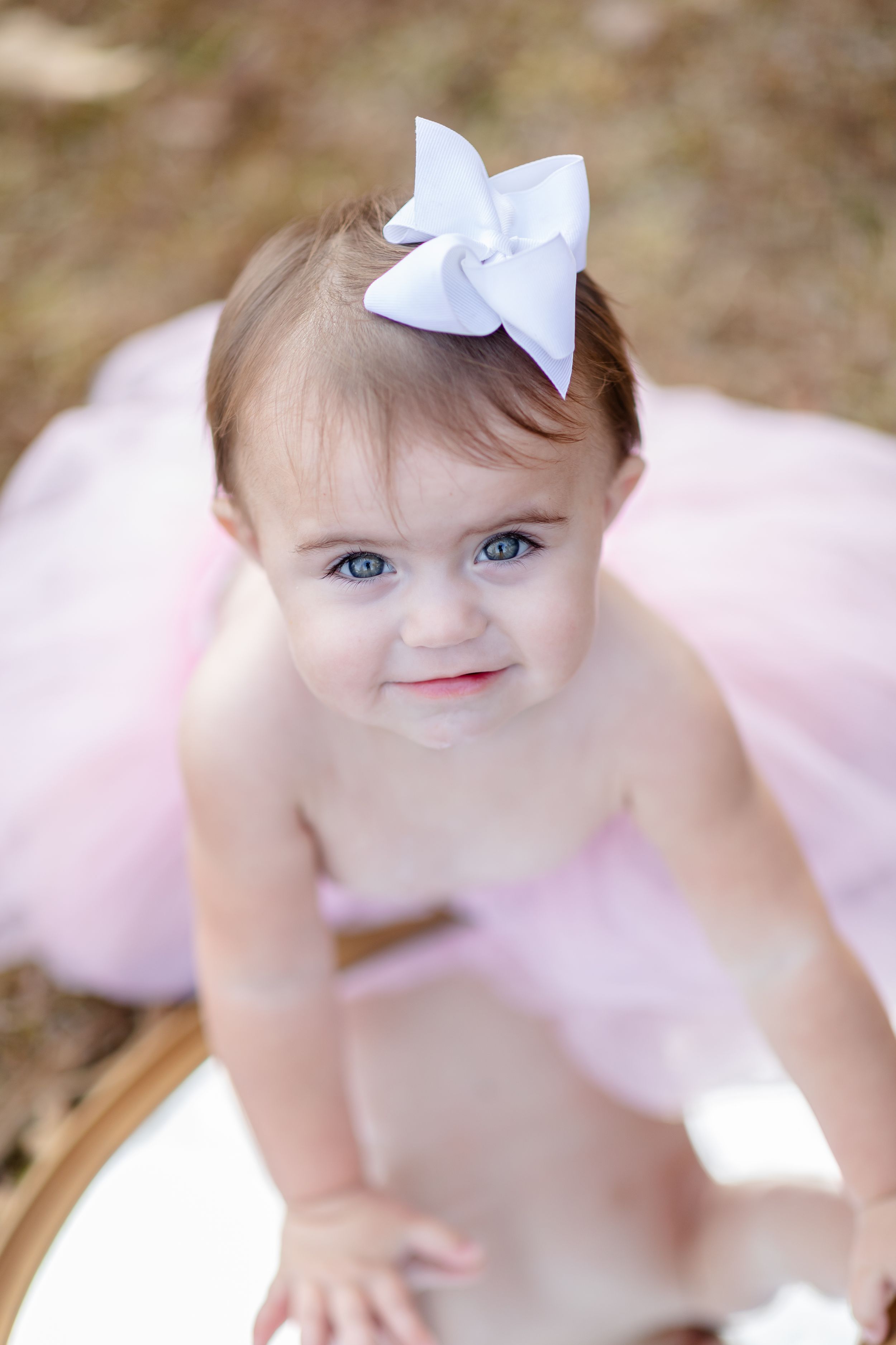 Delicate portrait session in pink dress with soft natural lighting and white bow accent.