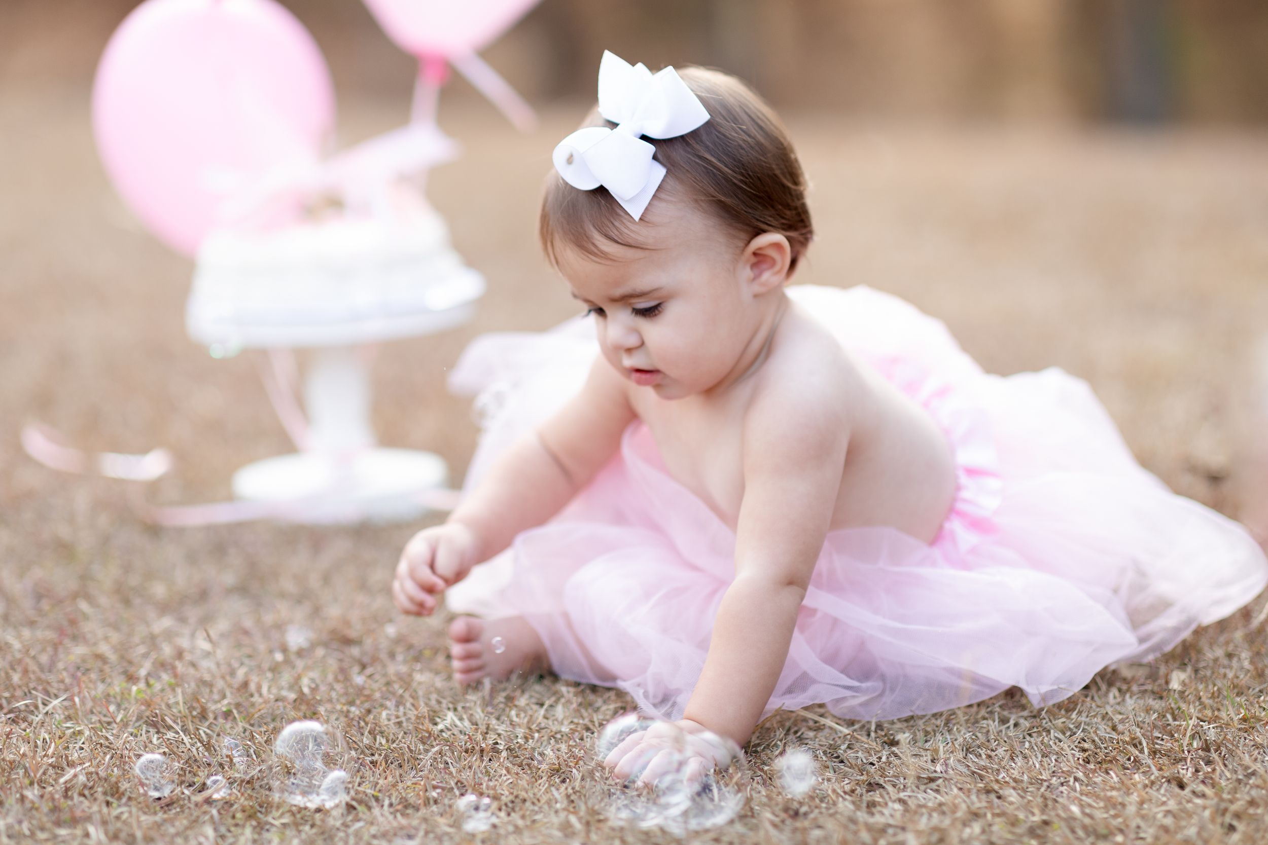 Dreamy outdoor photo shoot with pink dress and bubbles floating in natural light.