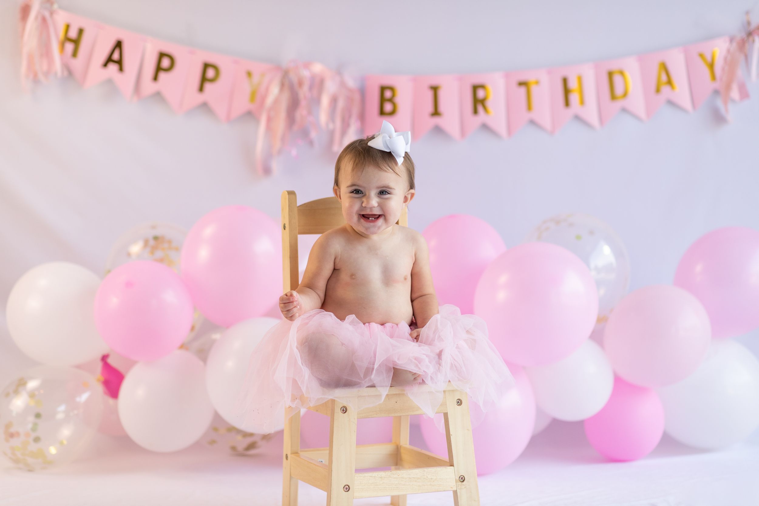 Pink and white birthday celebration setup with 'Happy Birthday' banner and balloons.