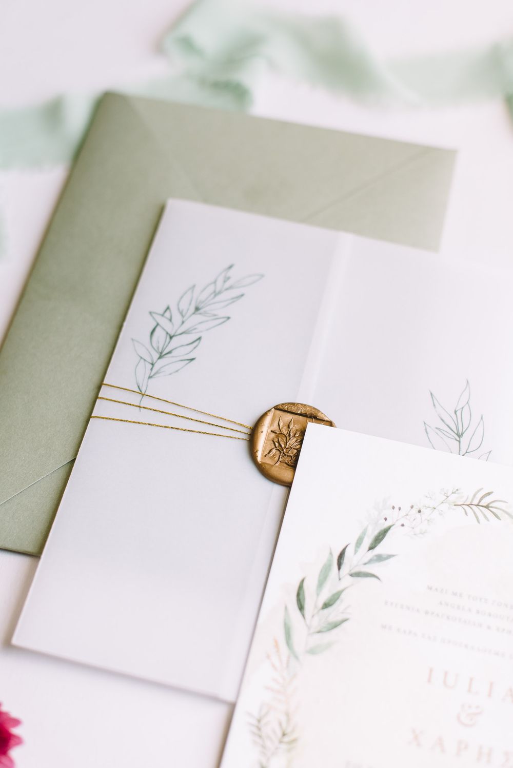 Elegant white wedding invitation suite with delicate botanical illustrations and gold wax seal details.