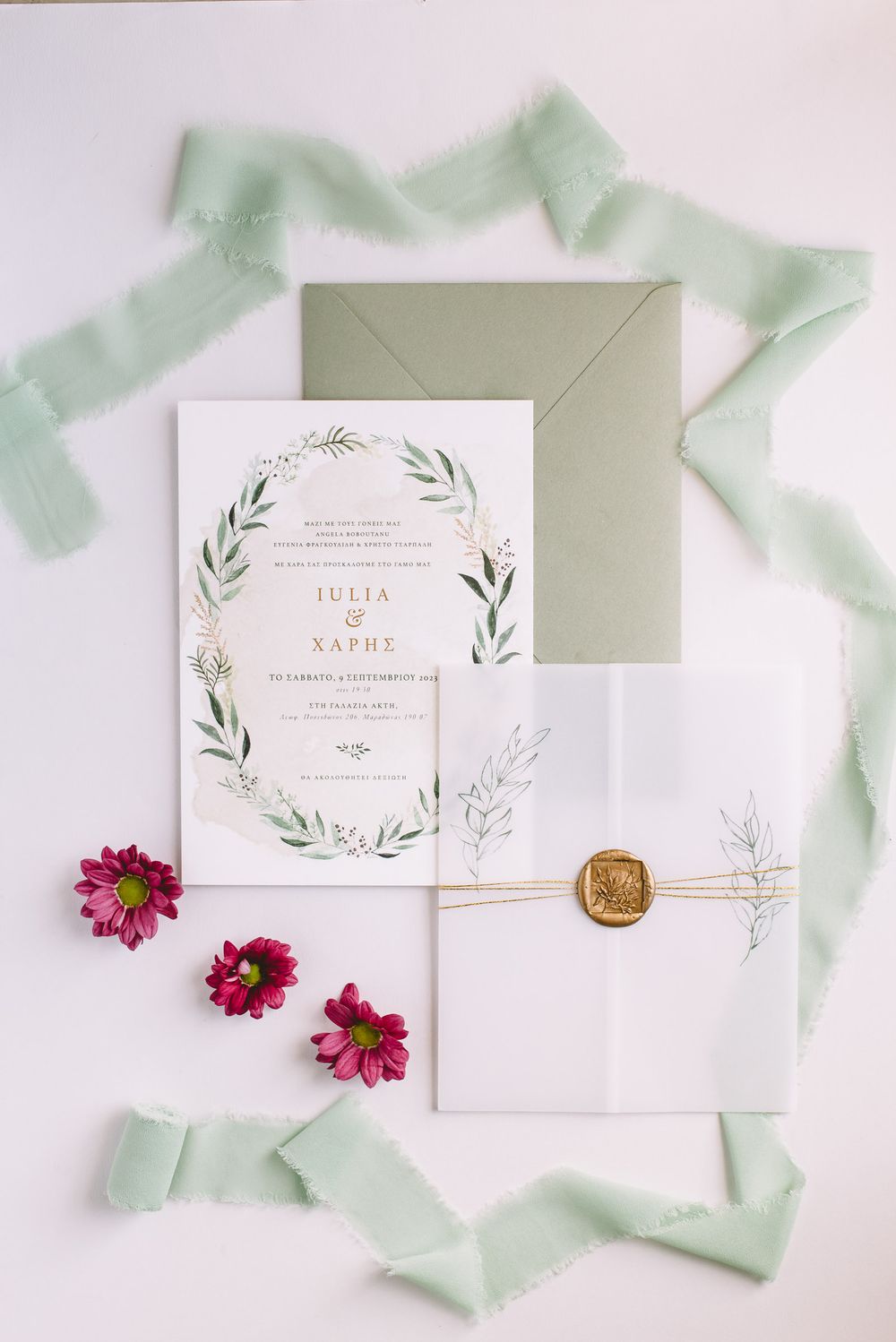 Elegant wedding invitation suite with delicate greenery design, pink flowers and sage green envelopes on white background.