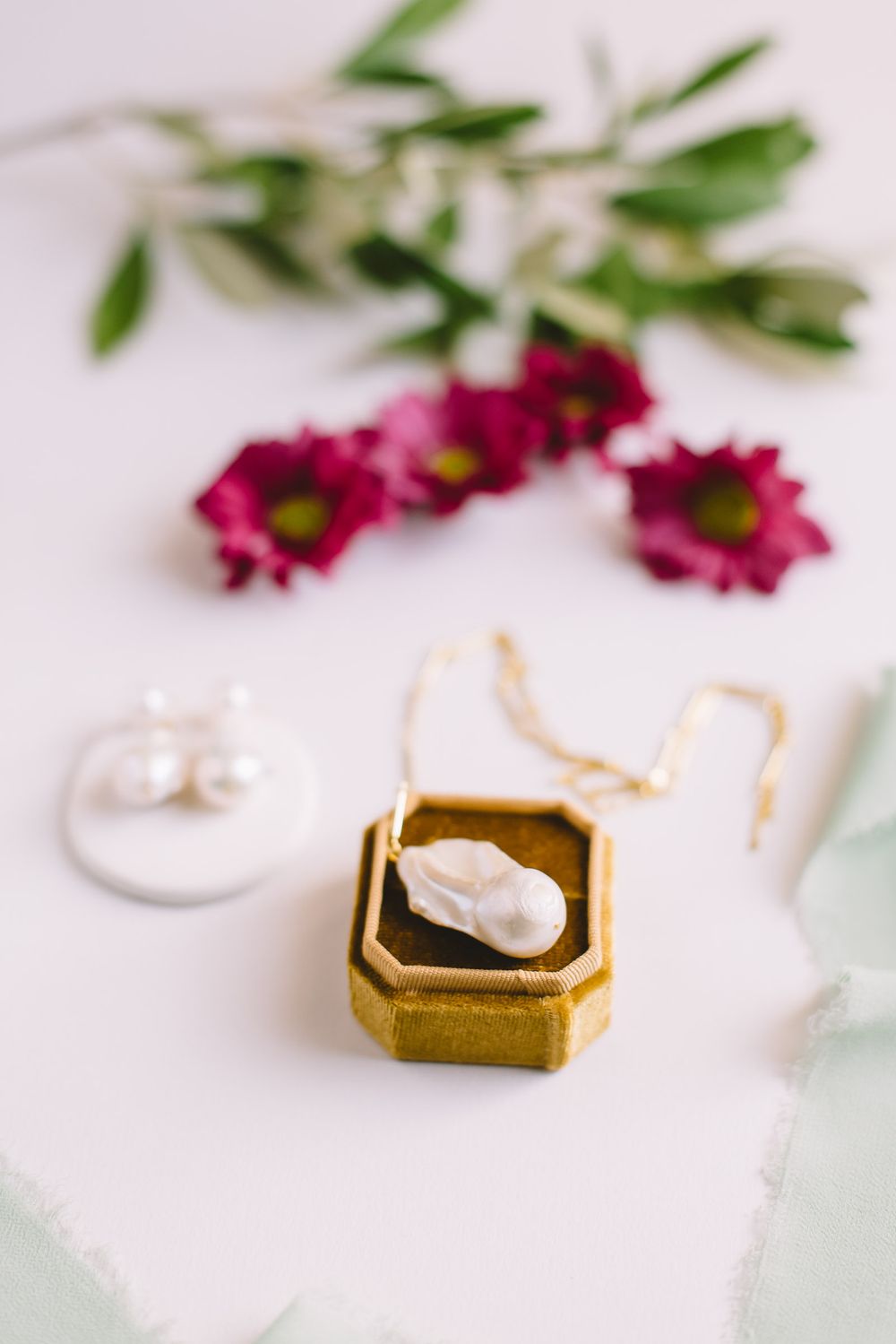 Wedding rings displayed in gold and white velvet ring boxes with pink flowers and greenery.