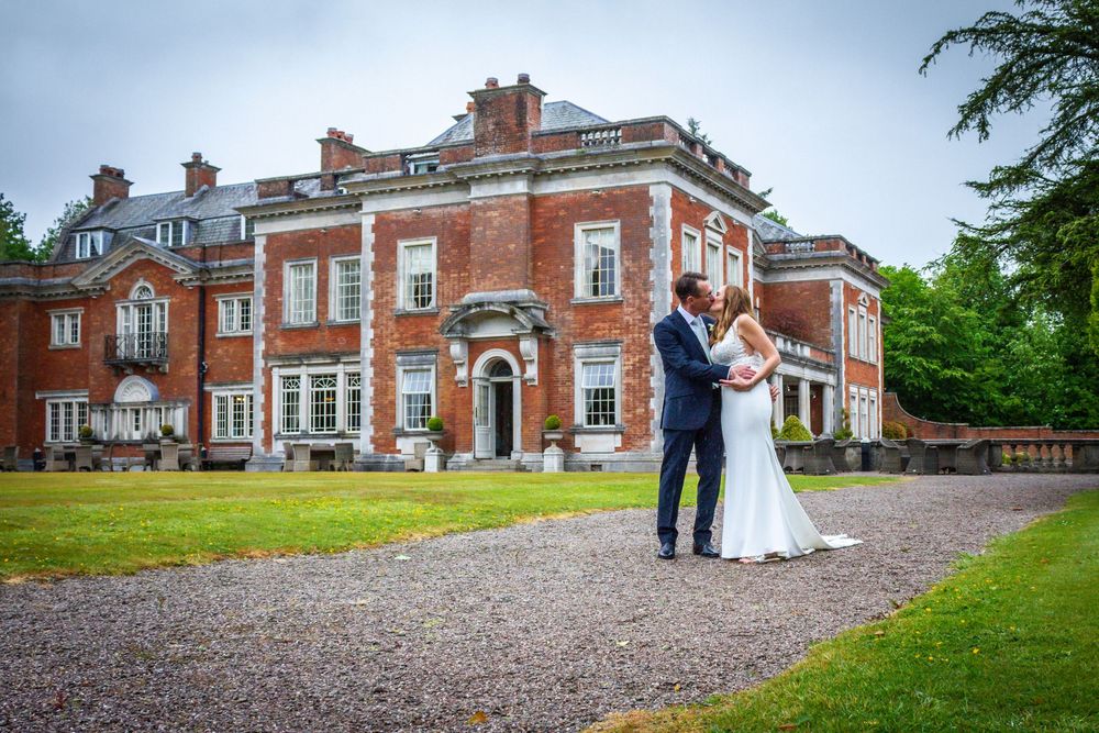 Bride and groom share a romantic moment outside a stunning red-brick English manor wedding venue.