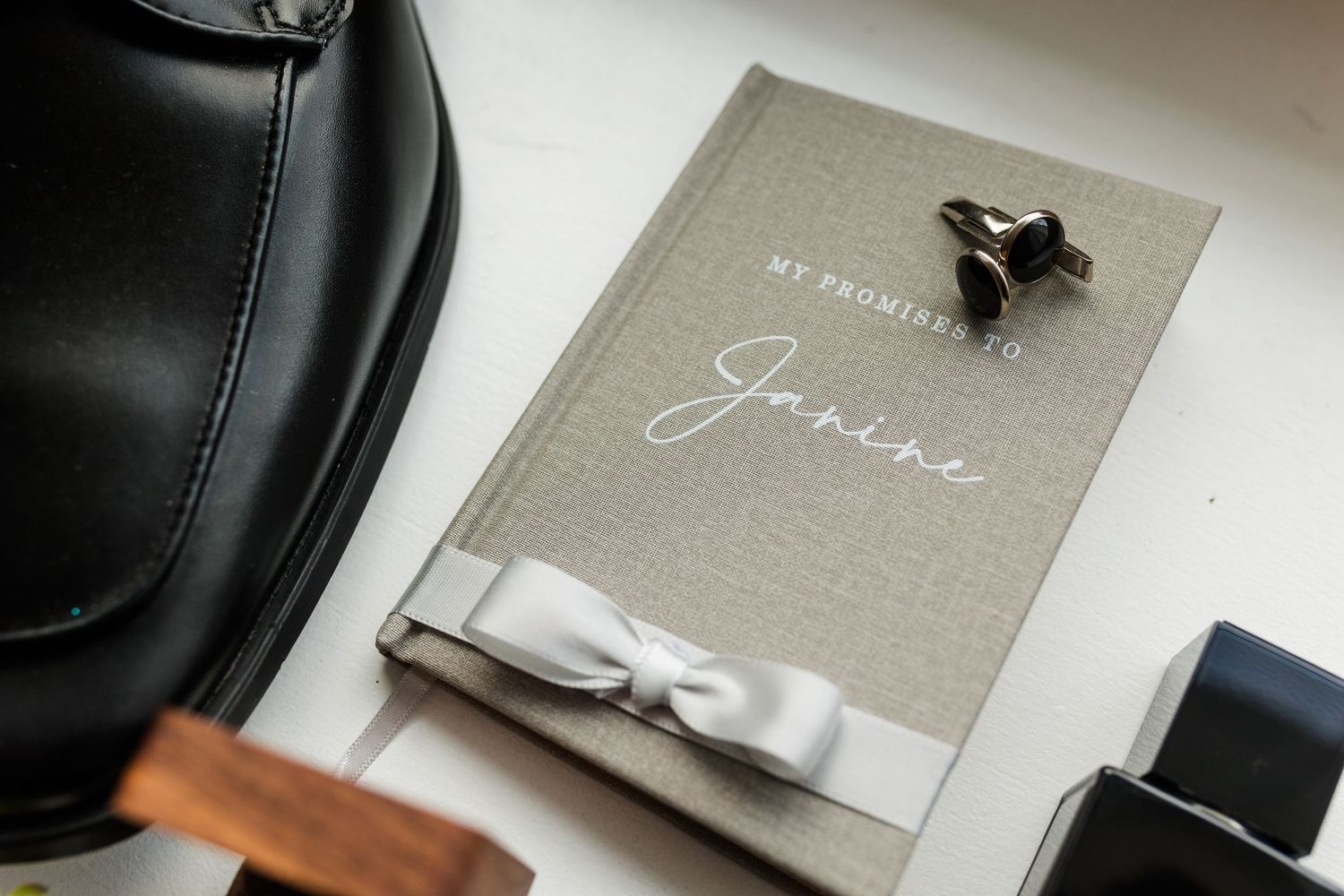 Elegant wedding photo album with gray linen cover and white bow displayed on dark surface.