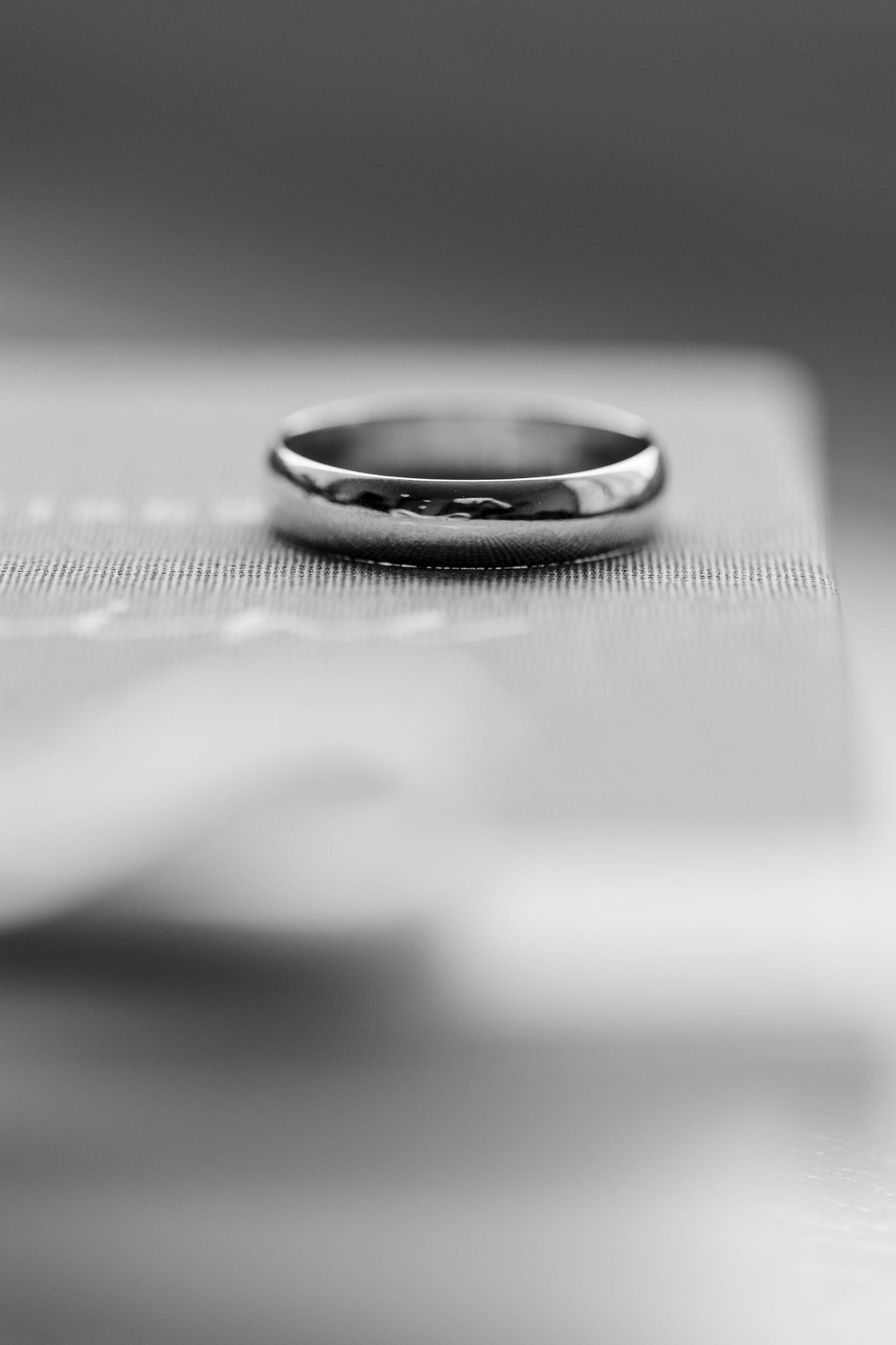 Black and white macro photograph of a wedding ring floating on a soft blurred background.