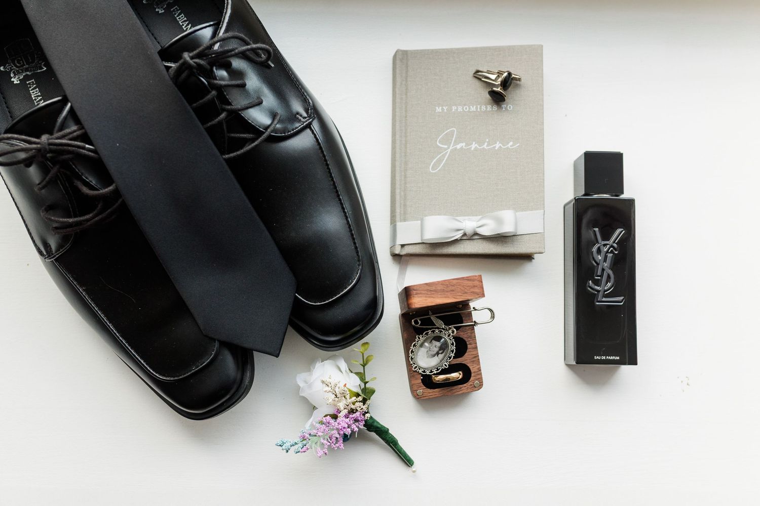 A collection of black leather dress shoes and cologne bottles arranged in a flat lay style against a white background.