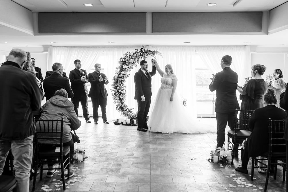 People gather in a bright room with tables and chairs for a social event or celebration.